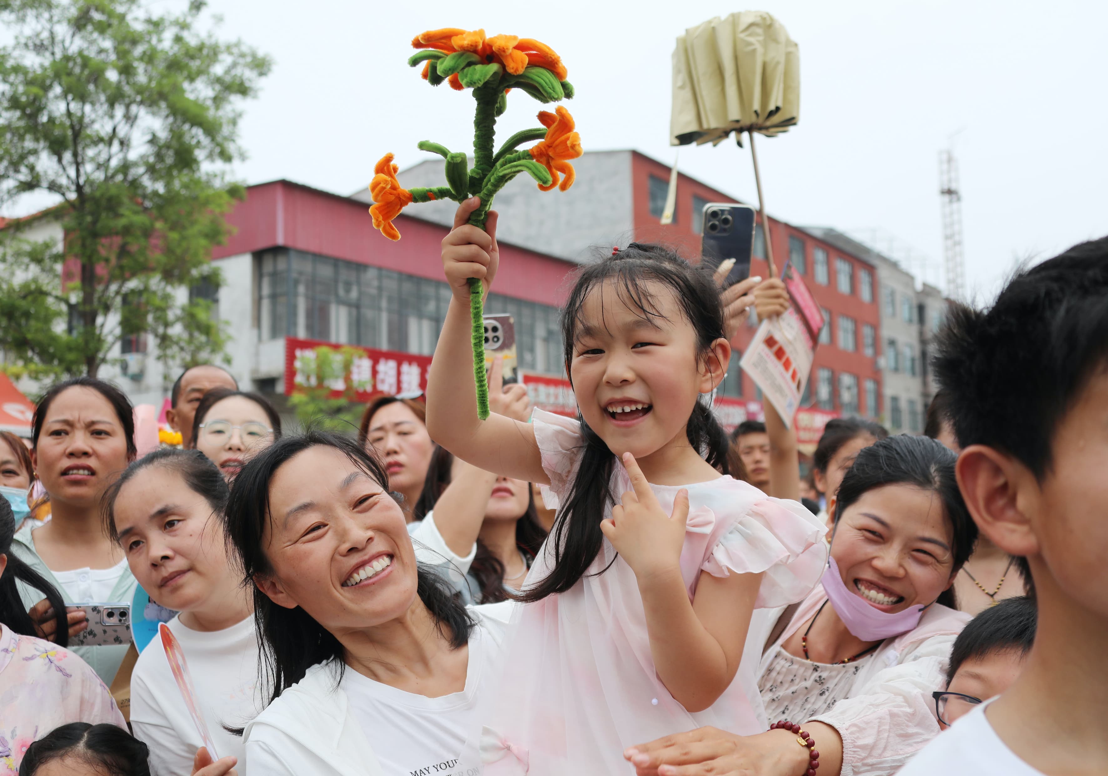 2025年6月7日上午11时，在尉氏县实验中学考点，一手执葵花的小女孩为参加高考的哥哥加油鼓劲。.jpg
