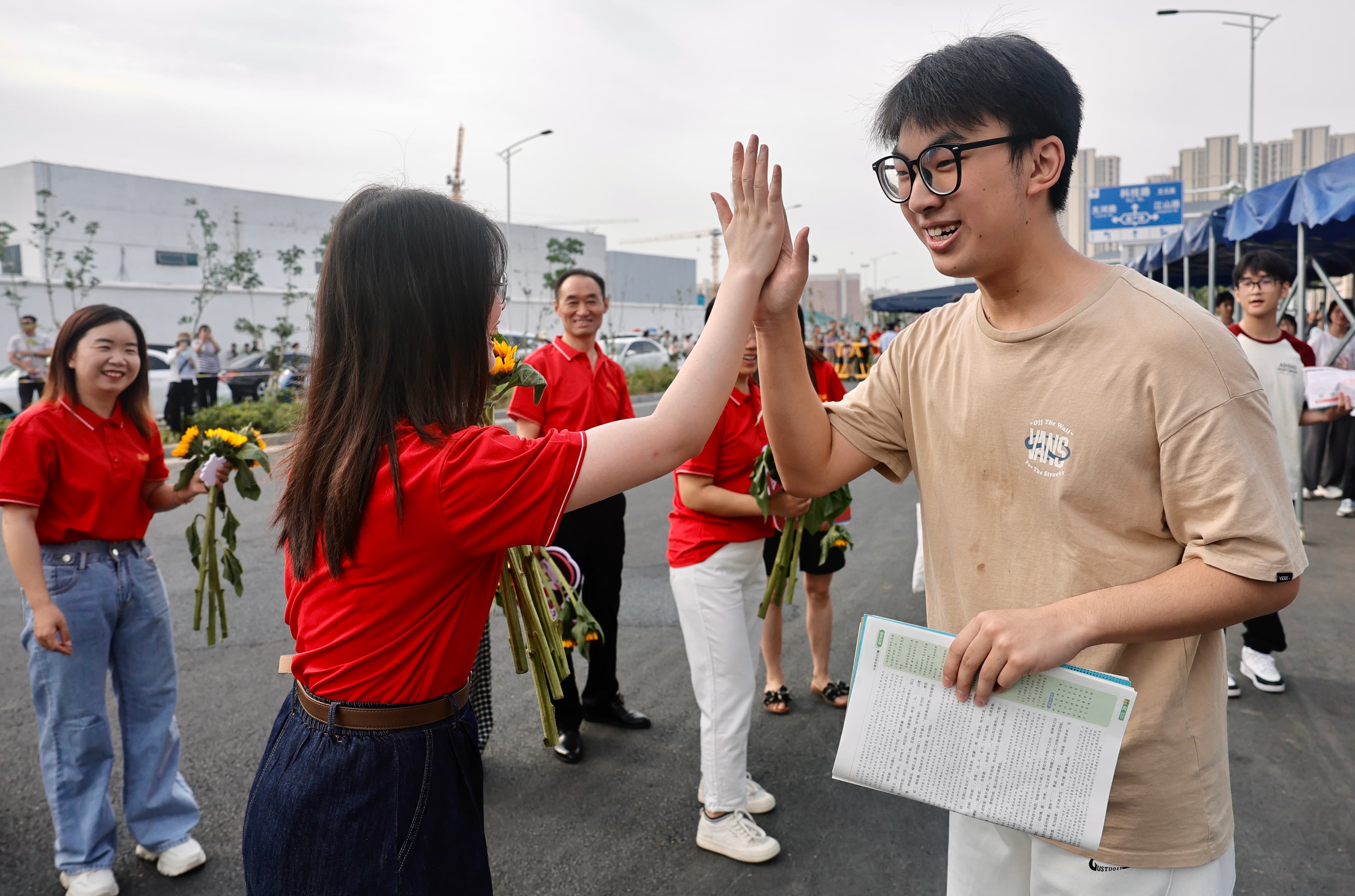 6月7日，郑州市第四高级中学考点，送考老师和考生逐一击掌，为其加油鼓劲。 本报记者王铮摄.jpeg
