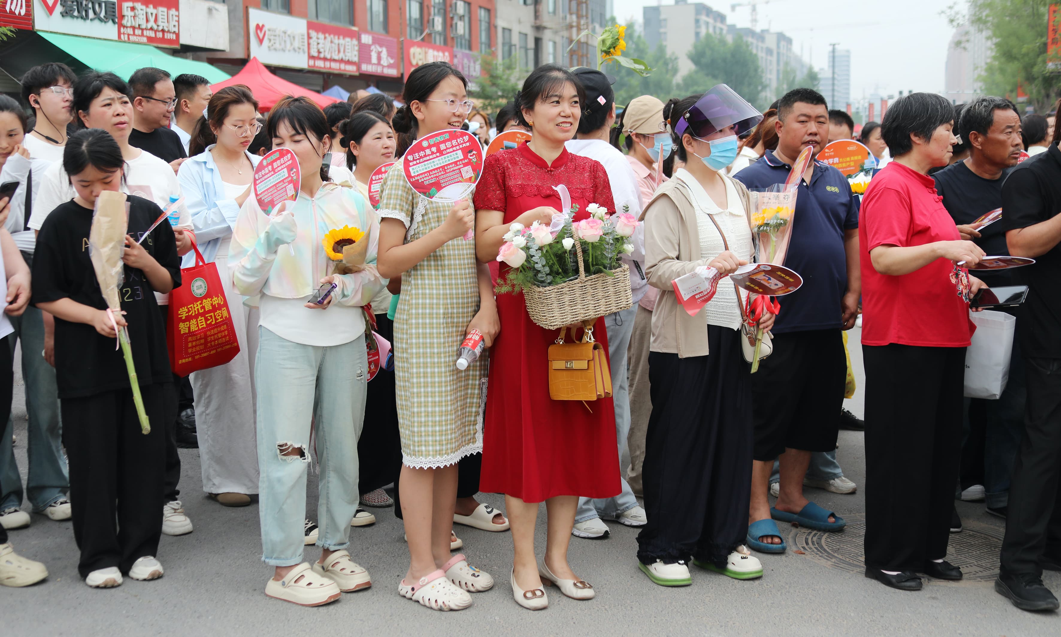 2025年6月7日上午11时，在尉氏县实验中学考点，身着旗袍、手执葵花的送考家长为考生加油鼓劲。.jpg